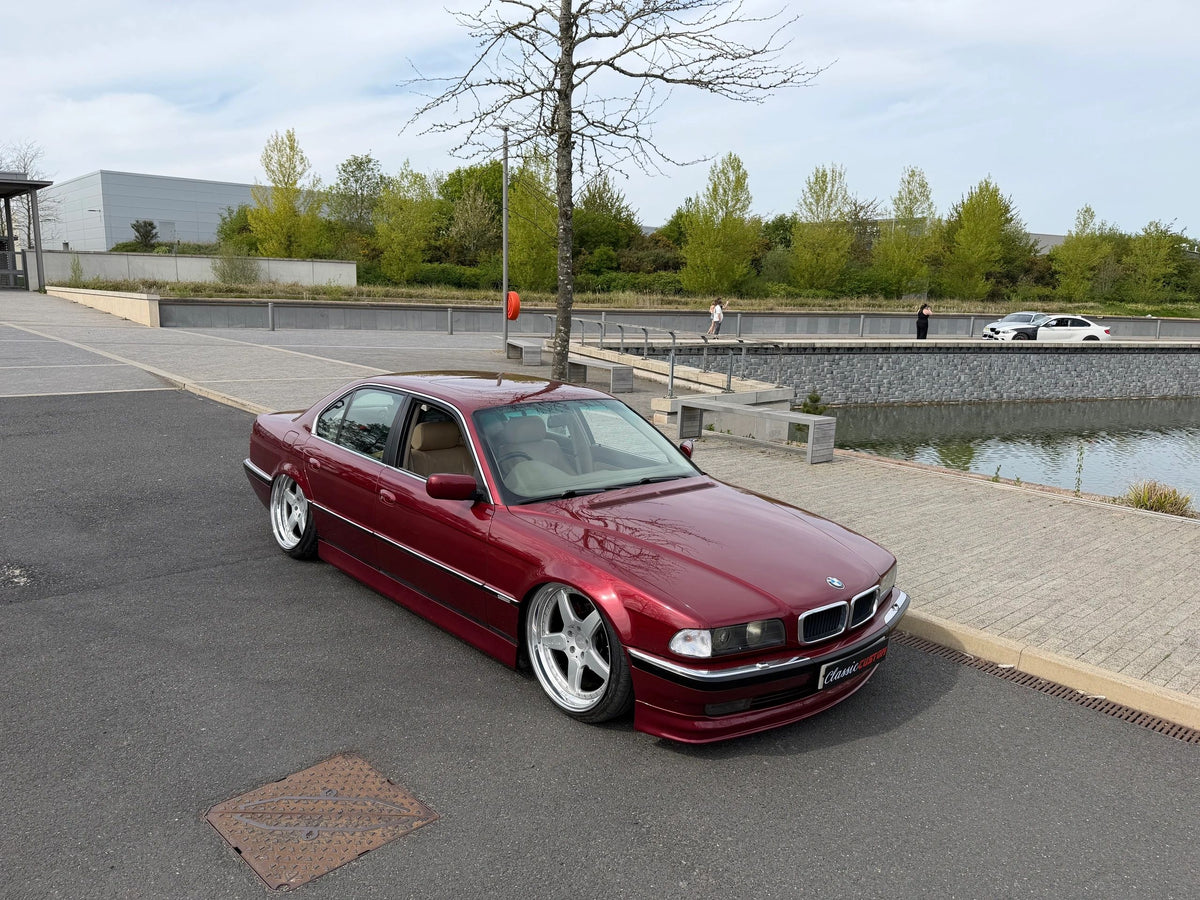 Burgundy BMW E38 sitting low on polished wheels